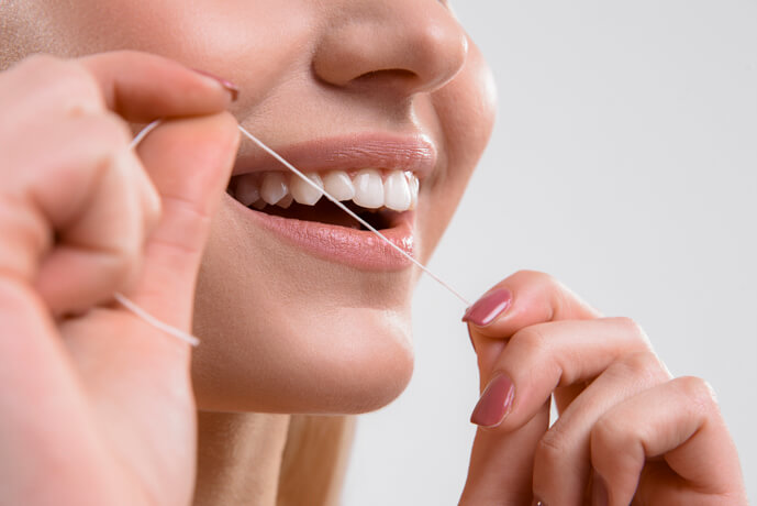 Mujer utilizando el hilo dental antes del cepillado.
