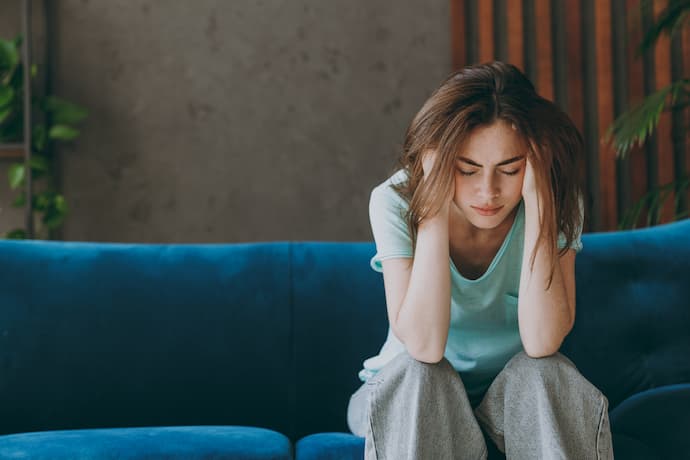 mujer triste sentada en sofá