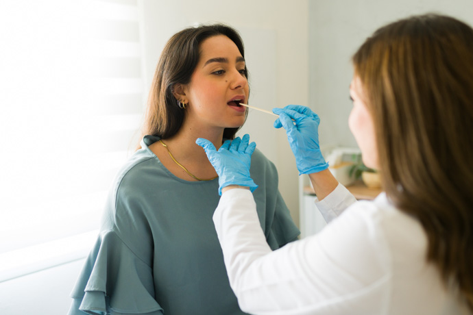 Médico examinando los pólipos en la garganta de una paciente.