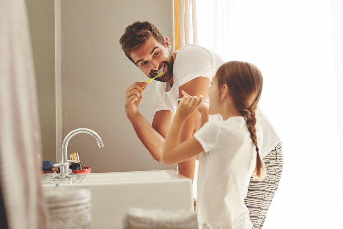 Padre e hija lavándose los dientes.