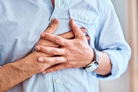 hombre sujetándose con las manos por la presión en el pecho y la falta de aire